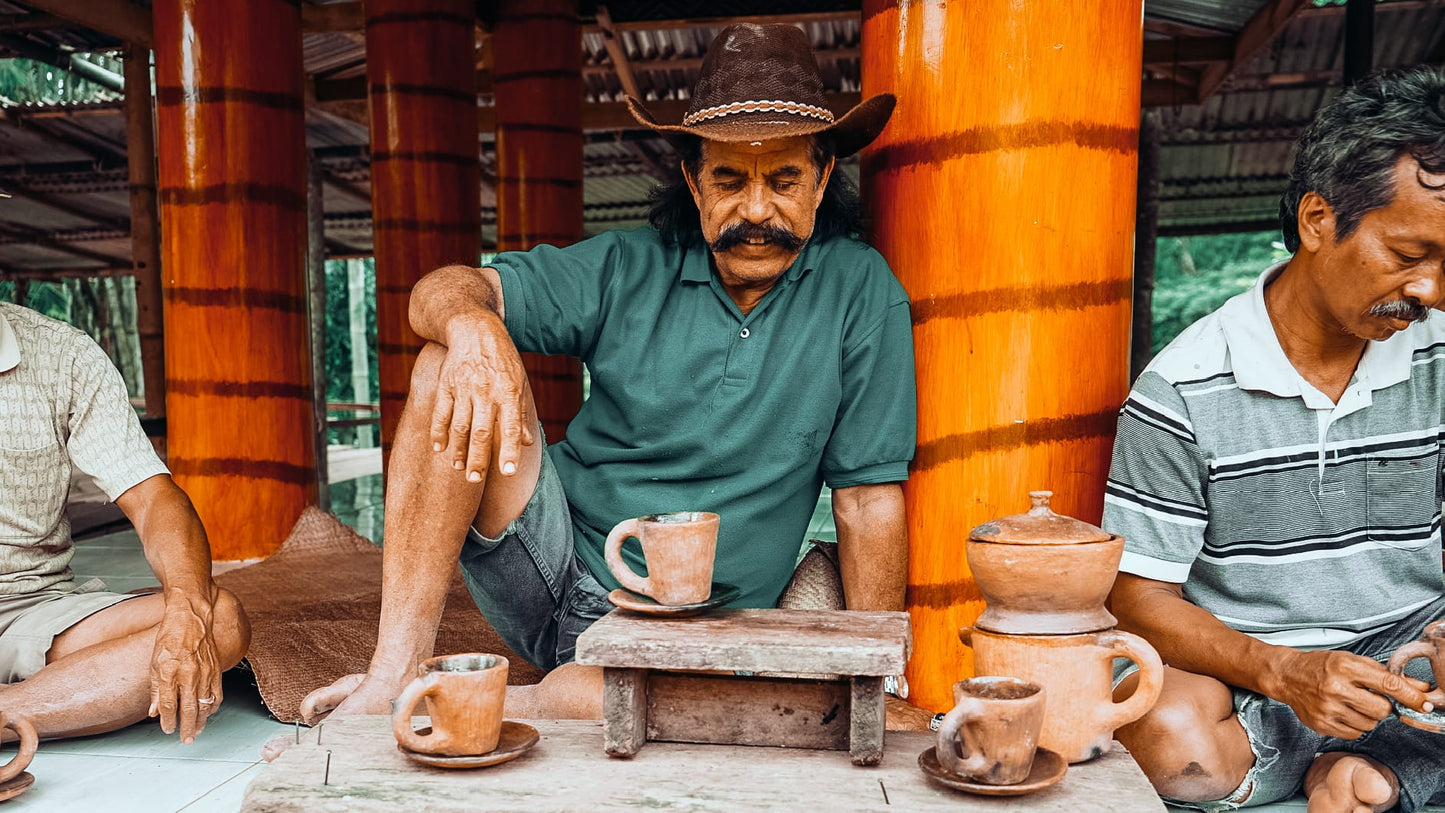 Torajan villagers drinking coffee from traditional clay earthenware